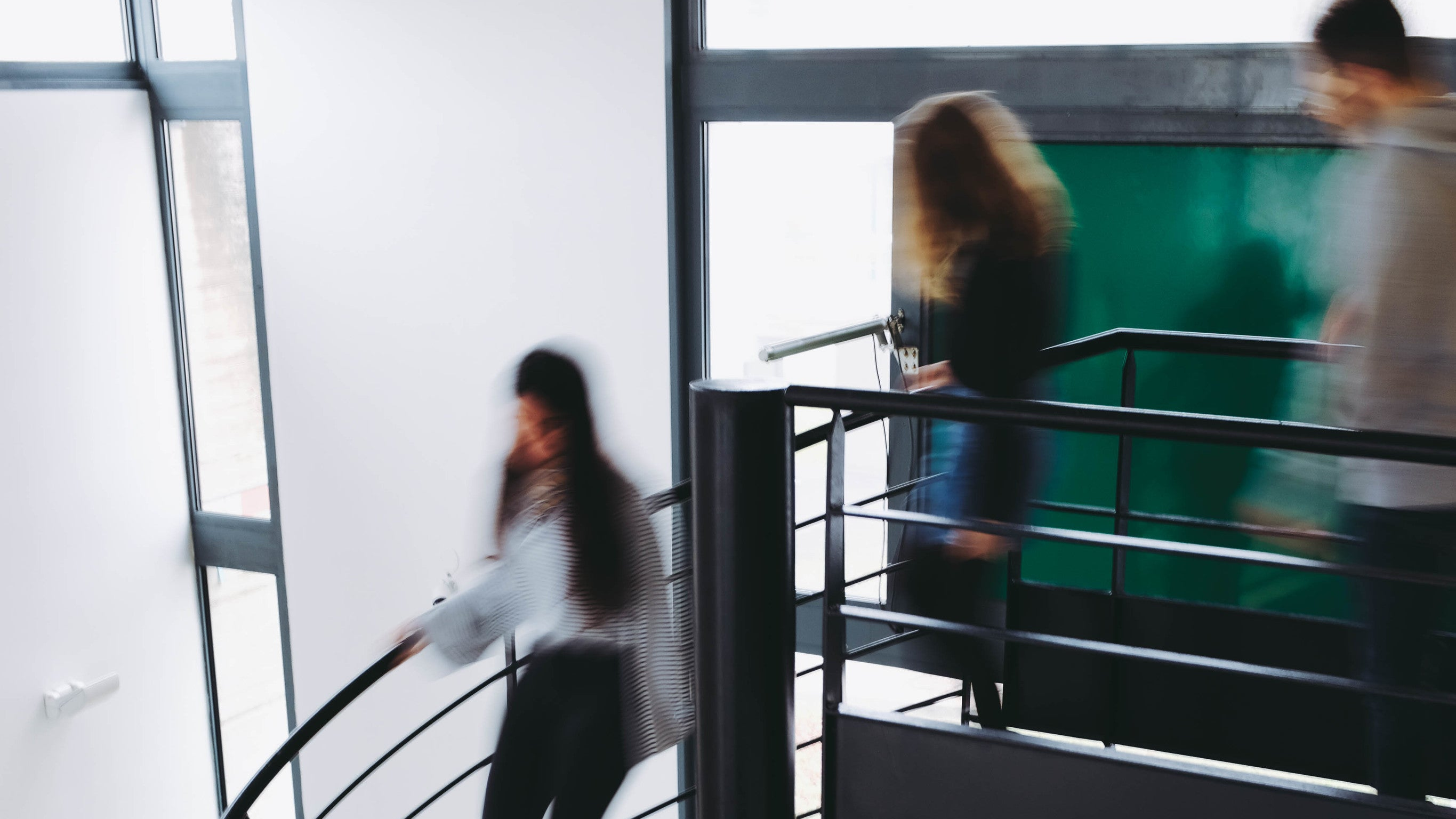 Students walking down a spiral staircase inside a college building